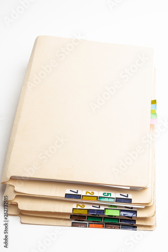 A stack of color-coded and numbered yellow file folders containing sheets of papers, files and documents set on a white background.