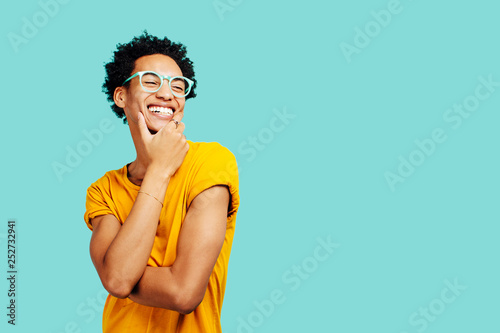 Portrait of a smiling young man with eyes closed, isolated on blue background