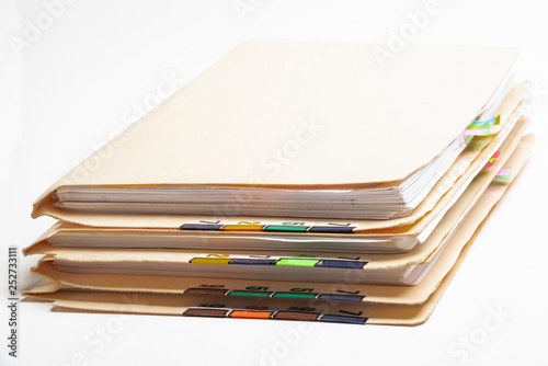 A stack of color-coded and numbered yellow file folders containing sheets of papers, files and documents set on a white background.