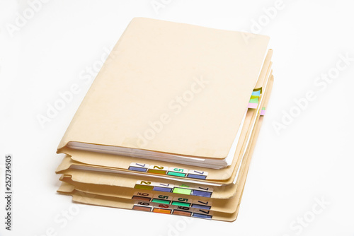 A stack of color-coded and numbered yellow file folders containing sheets of papers, files and documents set on a white background.