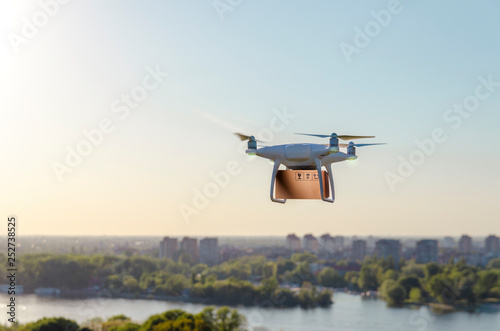 Drone carrying delivering package , city in background
