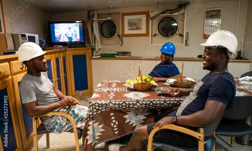 Seamen crew onboard a ship or vessel having fun watching TV. Recreation during at sea photo