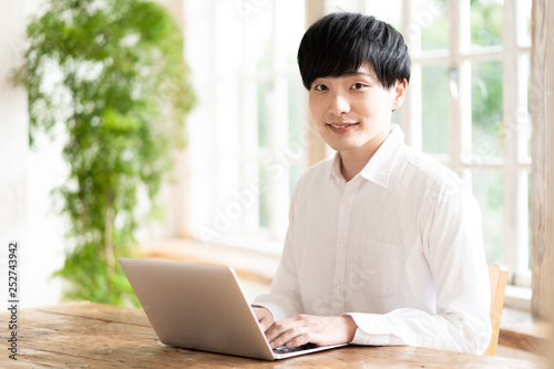 young asian man using laptop in living room © taka