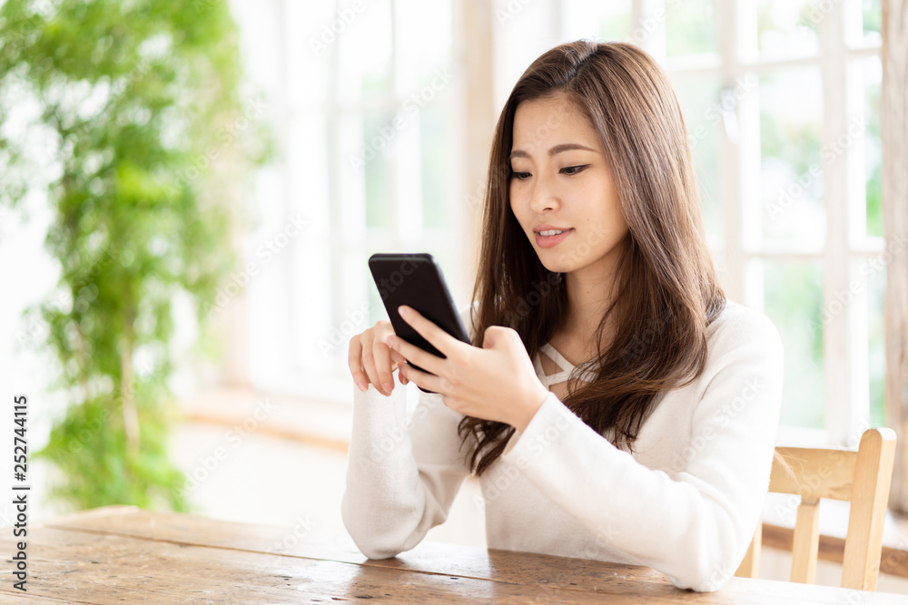 attractive asian woman using smart phone in living room attractive asian woman using smart phone in living room