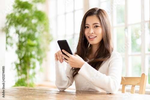 attractive asian woman using smart phone in living room