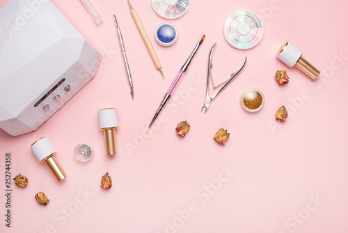 Beauty accessories for manicure and pedicure on a pink background,. Samples of nail polish, scissors, manicure ultraviolet machine, nippers and other accessories for home and salon procedures