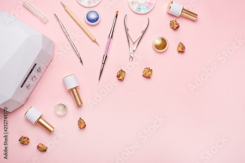 Beauty accessories for manicure and pedicure on a pink background,. Samples of nail polish, scissors, manicure ultraviolet machine, nippers and other accessories for home and salon procedures