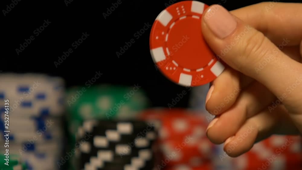 Lady rotating poker chip in hand, pondering on strategy of game, fortune sign Lady rotating poker chip in hand, pondering on strategy of game, fortune sign