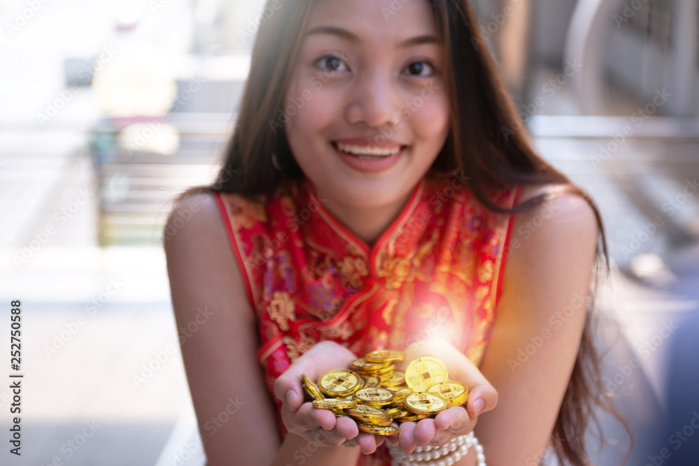 Young woman wearing traditional Chinese dress with two hands holding stack of Chinese ancient gold coin, the Chinese word on gold means 