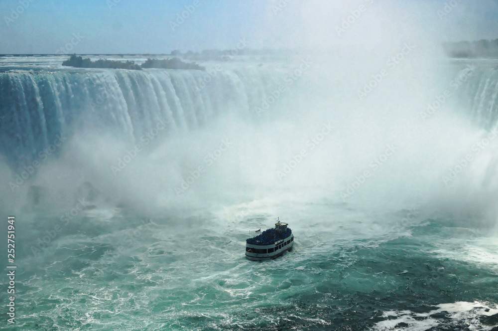 Touristic boat approaching the middle of the Niagara Horseshoe Falls bowl. The falls height is 57 m and they throw down about 6,400 m3 water per second