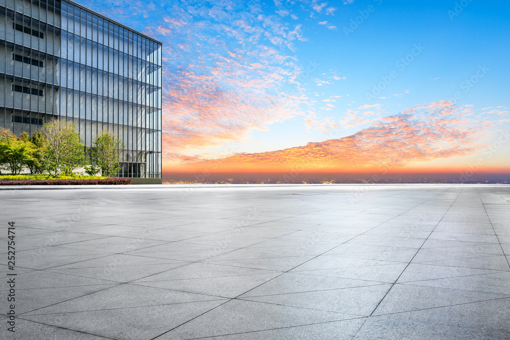 Empty square floor and modern city skyline with buildings at sunset