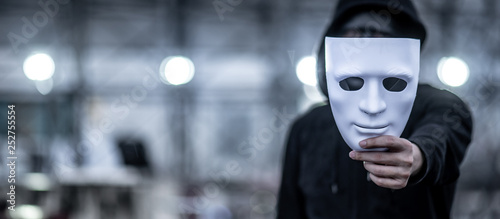 Bild auf Leinwand Mystery hoodie man with black mask holding white mask in his hand