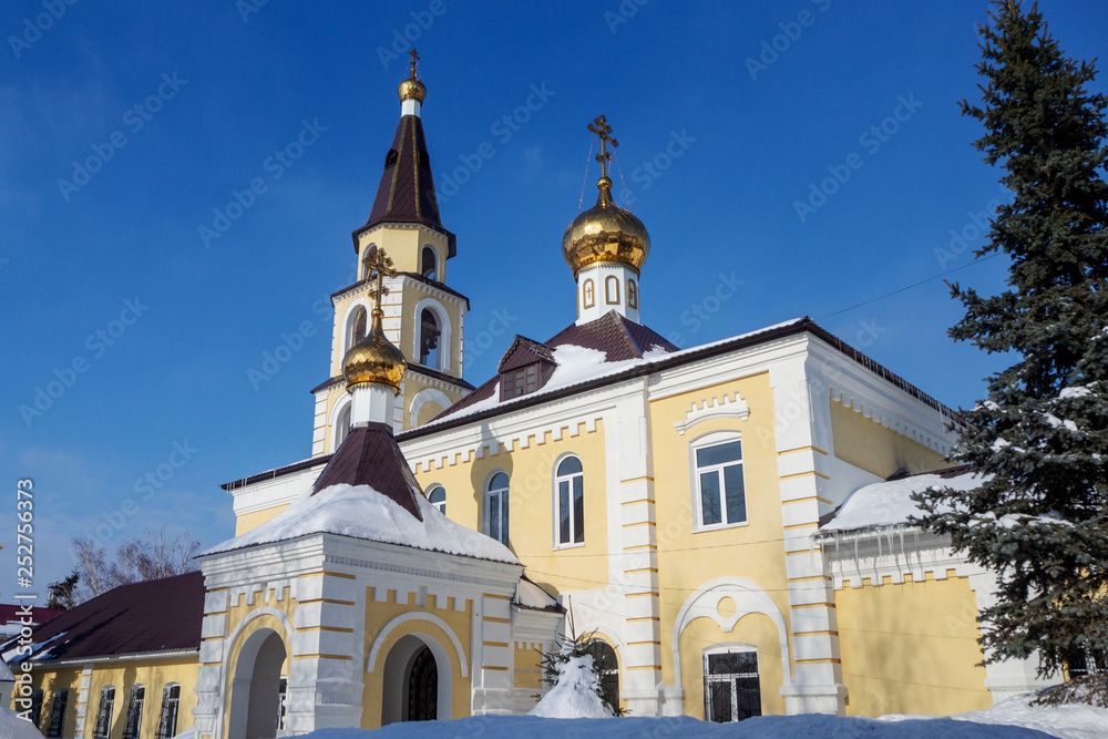 Orthodox temple with golden crosses and domes against the blue sky.