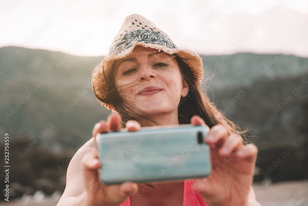 Beautiful smiling girl taking a picture with her smartphone. Pretty woman has fun.