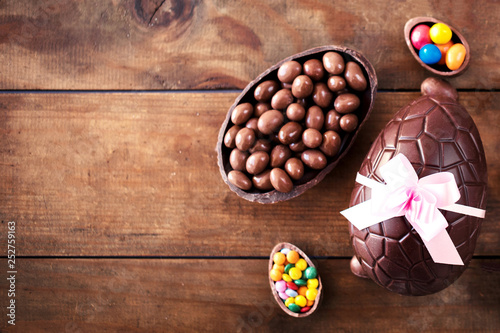 Chocolate Easter eggs on wooden background with ribbon bow and candies. Happy Easter!.