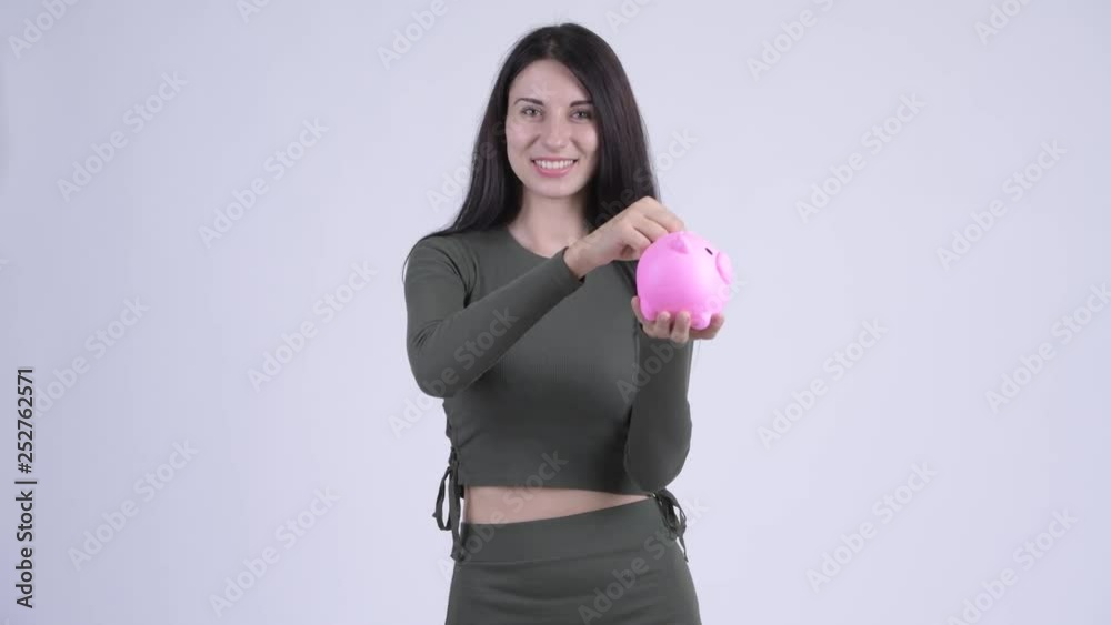 Happy young beautiful woman inserting coin to piggy bank Happy young beautiful woman inserting coin to piggy bank