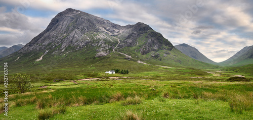 Panorama of white cottage on River Coupall valley with Stob Dhearg peak of Buachaille Etive Mor range at Glen Coe Scottish Highlands Scotland