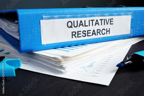 Qualitative research methods report in a blue folder. photo