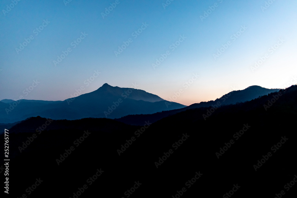 Dark sunrise landscape with mountain silhouettes on a minimalistic nature scene