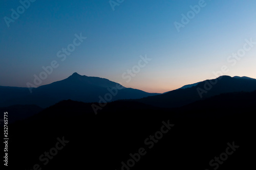 Dark sunrise landscape with mountain silhouettes on a minimalistic nature scene