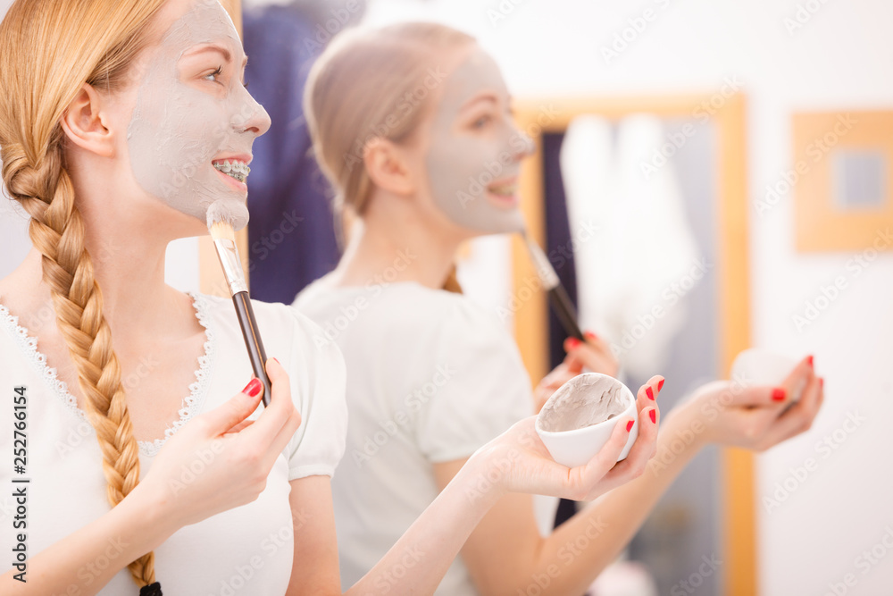 Woman applying with brush clay mud mask to her face Woman applying with brush clay mud mask to her face