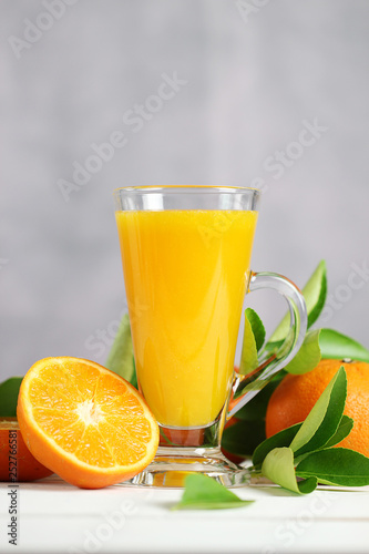 Glass of orange juice with oranges fruit on wooden table. Summer drink.