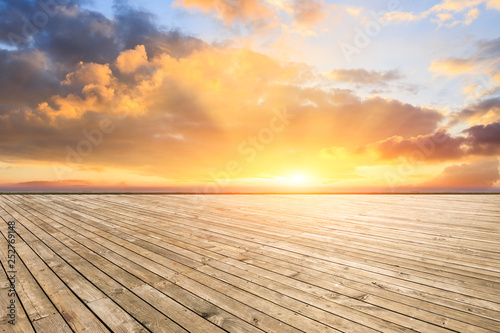 Empty wooden platform and modern city skyline with beautiful colorful clouds at sunset © ABCDstock