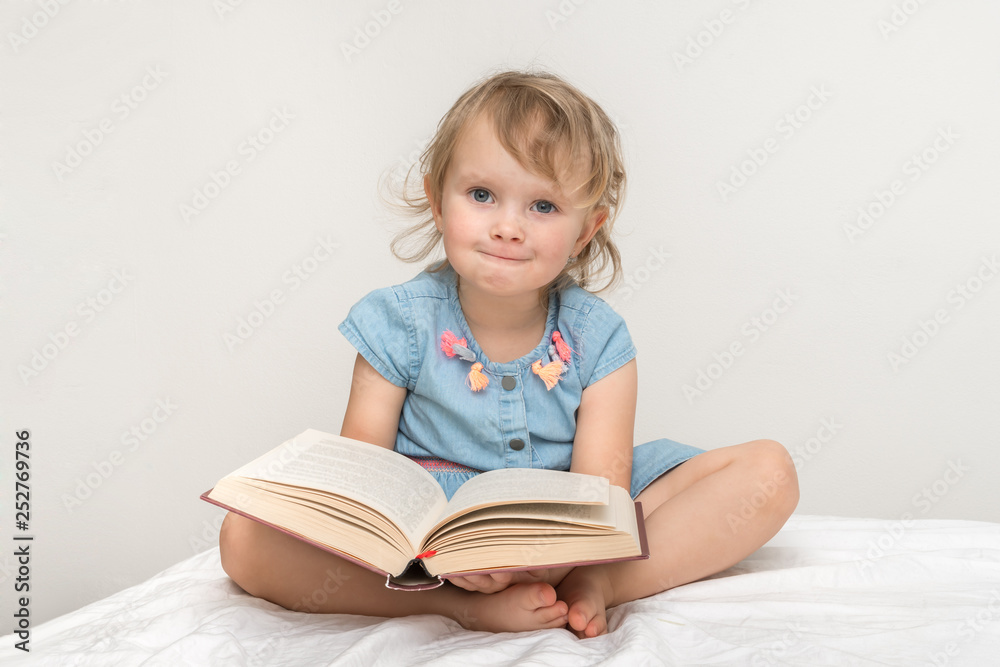 Cute little child in blue dress reading a book Cute little child in blue dress reading a book