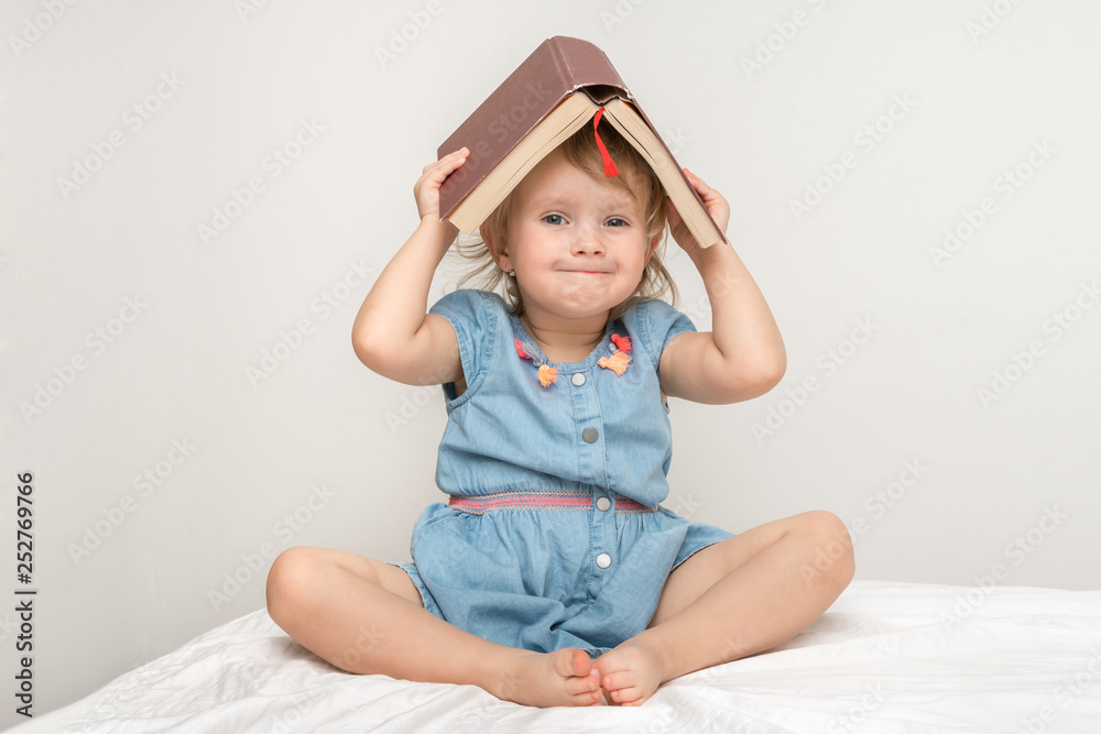 Cute little child in blue dress reading a book Cute little child in blue dress reading a book