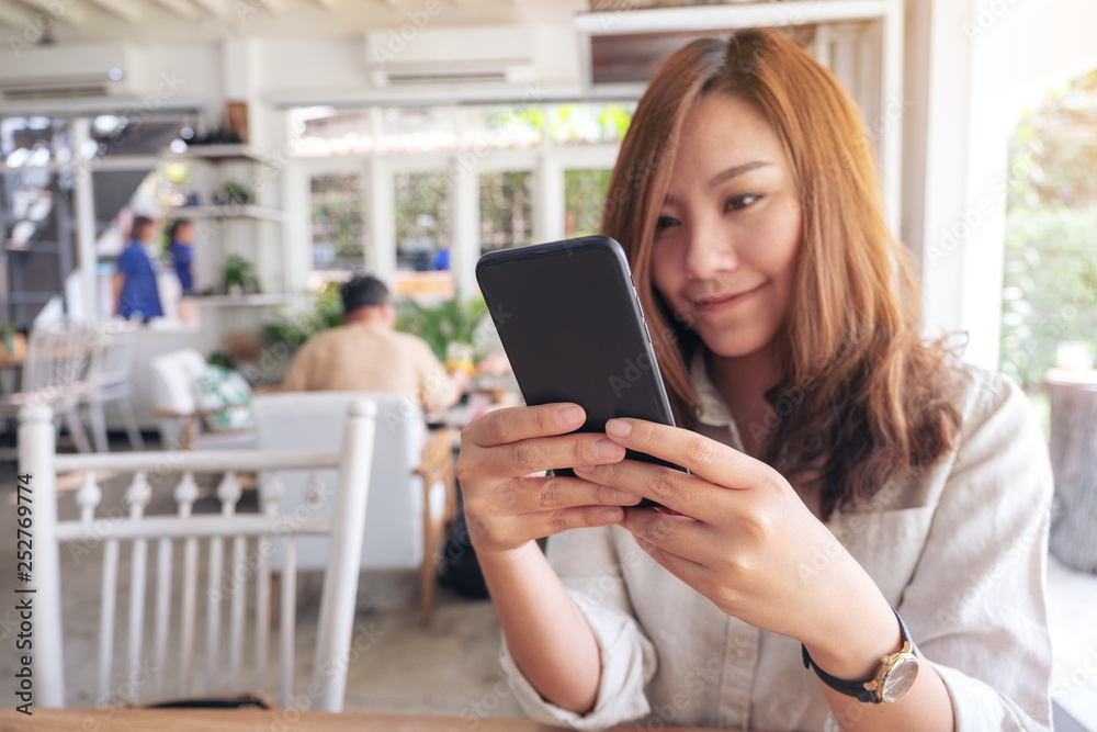 Closeup image of a beautiful woman holding , using and looking at smart phone in cafe Closeup image of a beautiful woman holding , using and looking at smart phone in cafe