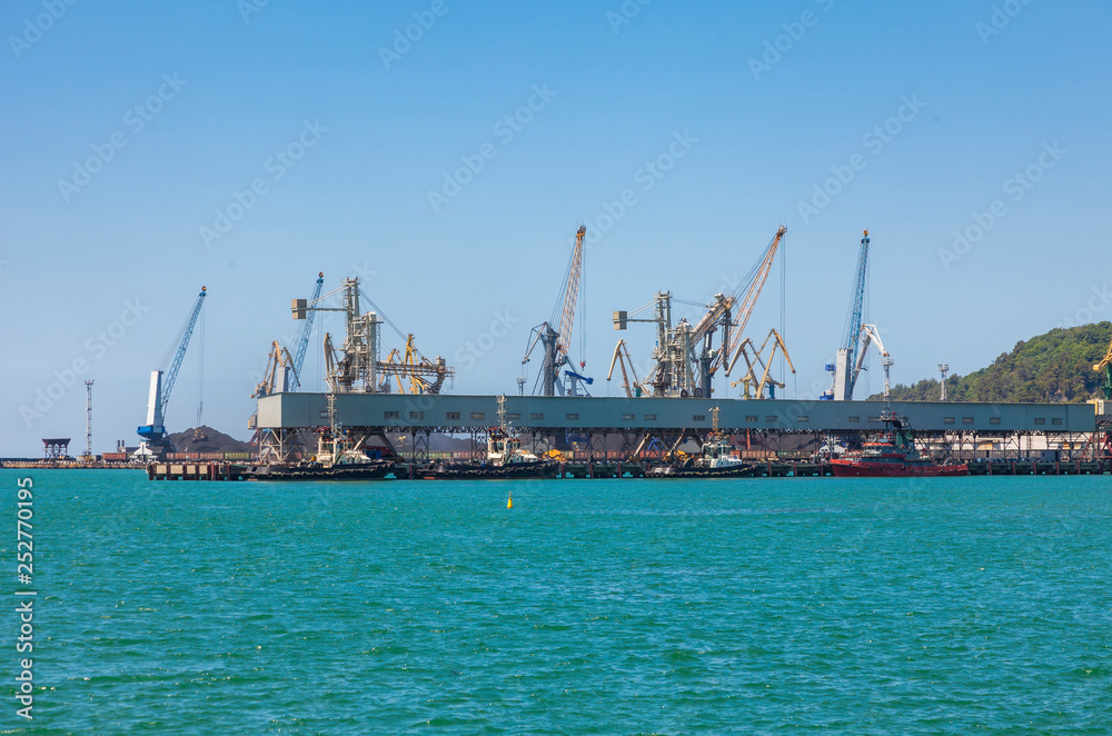Seaport area, cranes loading ships in port, logistic import export business and transportation