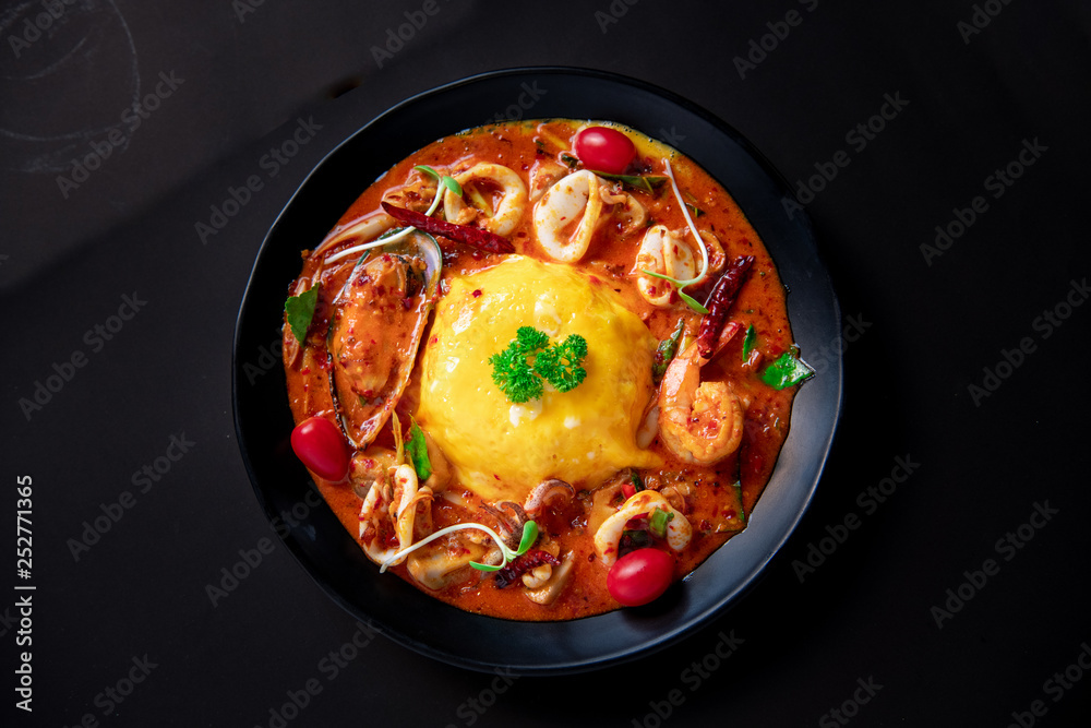 Thai Food Recipe .Thick rice soup, Tom Yum sauce, seafood .Thick egg rice On a black plate Thai Food Recipe .Thick rice soup, Tom Yum sauce, seafood .Thick egg rice On a black plate