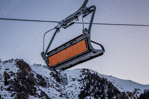 Empty ski lift with an empty orange commercial banner in front of morning sky
