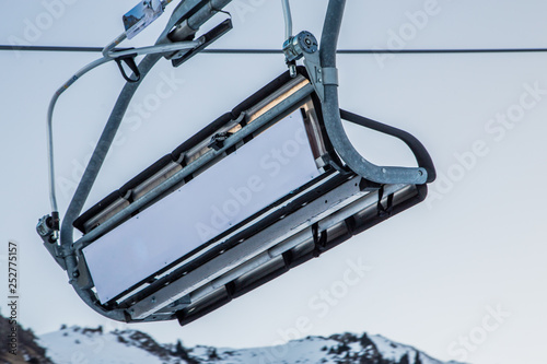Empty ski lift with an empty white commercial banner in front of morning sky