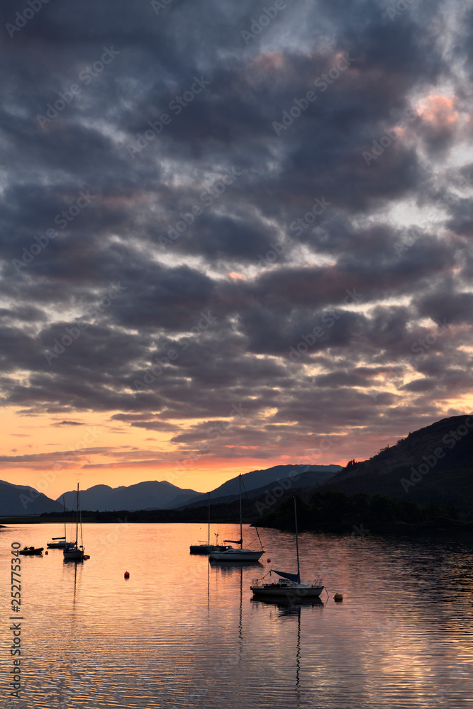 Red Sunset with clouds on Loch Leven with moored sailboats at Glencoe Boat Club Scottish Highlands Scotland UK