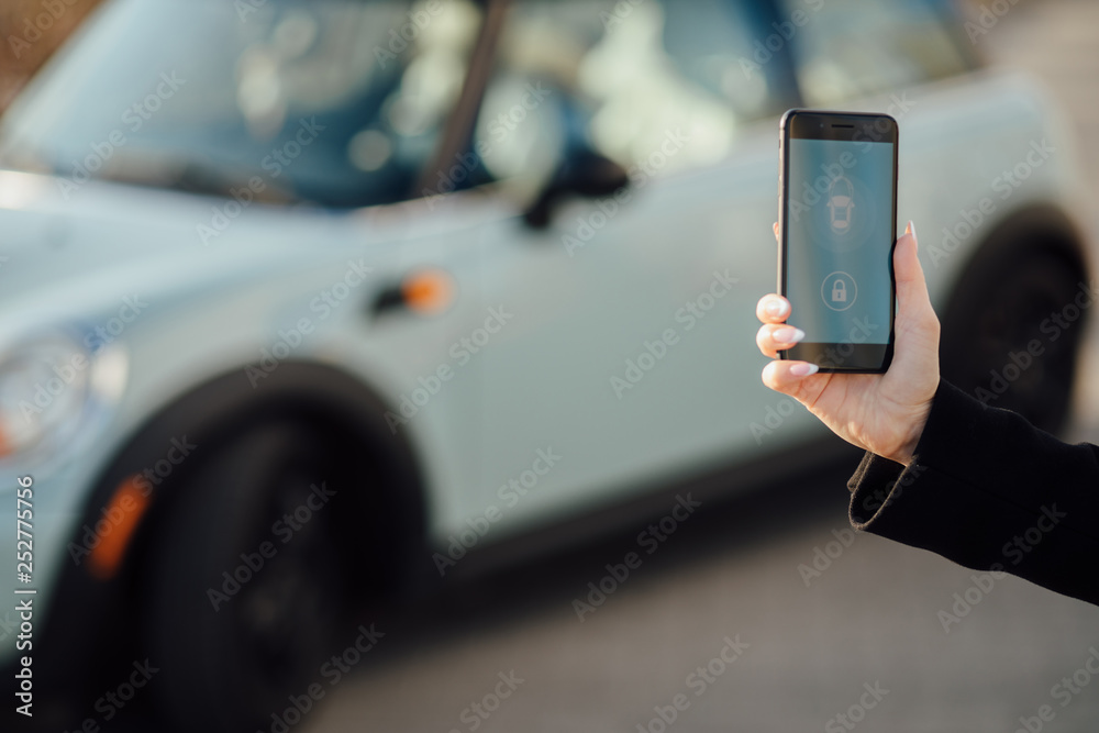 Woman using Smartphone near the car. Mobile phone apps for car owners concept.