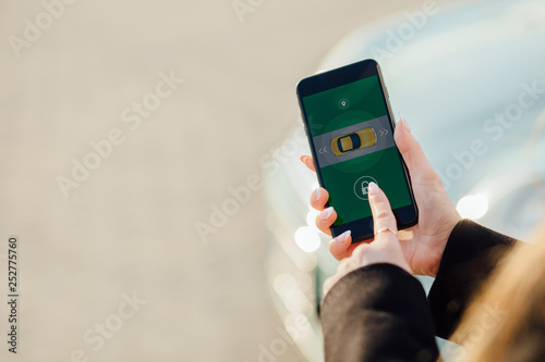 Woman using Smartphone near the car. Mobile phone apps for car owners concept.