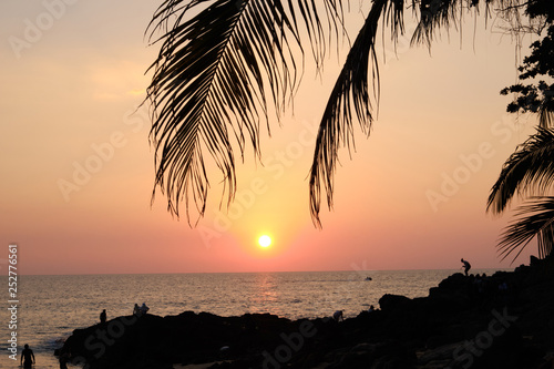 Sunset on tropical sea under palm trees and beach