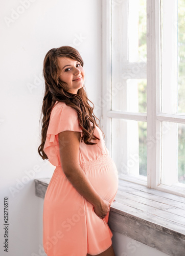 Beautiful smiling pregnant woman is holding belly