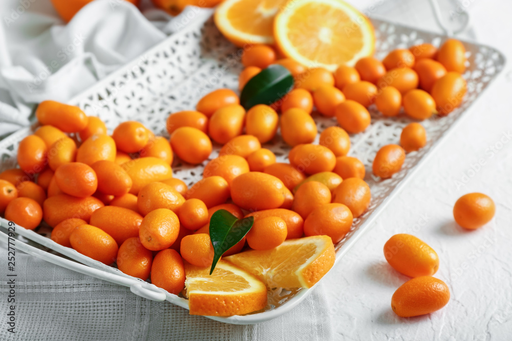 Tray with delicious kumquat fruit on table