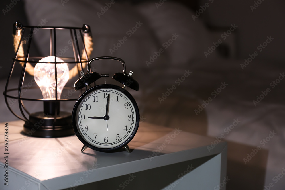 Naklejka premium Alarm clock on bedside table in evening