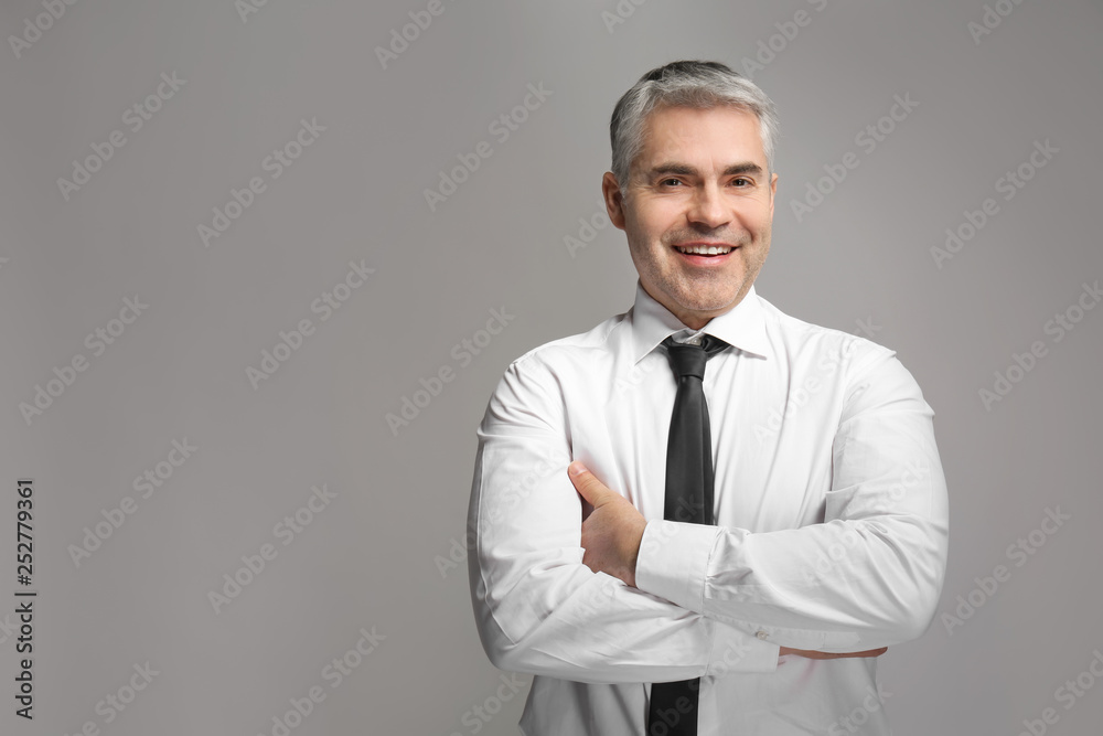 Handsome mature businessman on grey background Handsome mature businessman on grey background