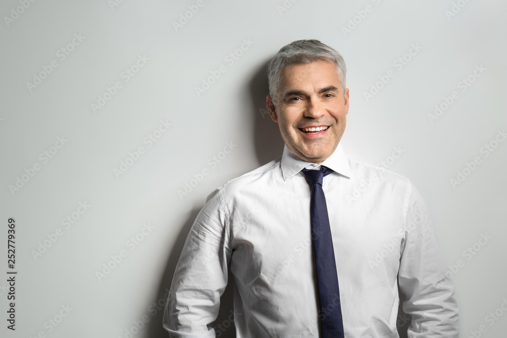 Handsome mature businessman on grey background Handsome mature businessman on grey background