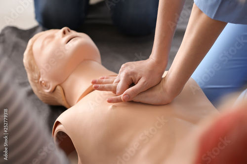 Instructor demonstrating CPR on mannequin at first aid training course photo