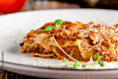 The concept of Italian cuisine. Lasagna with minced meat  bechamel sauce and parmesan cheese. Close up. Serving dishes in a restaurant in a white plate. copy space