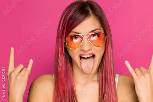 a happy woman with a pink hair and sunglasses on pink background