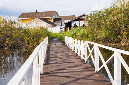 Village, nature and country life concept - long wooden bridge and houses