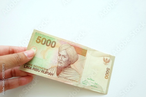  Woman hand holding Indonesia banknote on white background. 