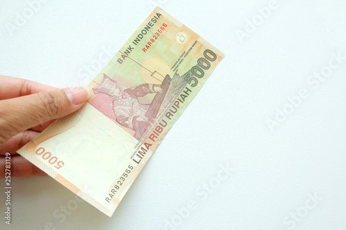  Woman hand holding  Indonesia banknote on white background. 