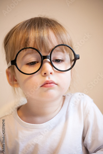 serious two years old girl in big black glasses on her nose